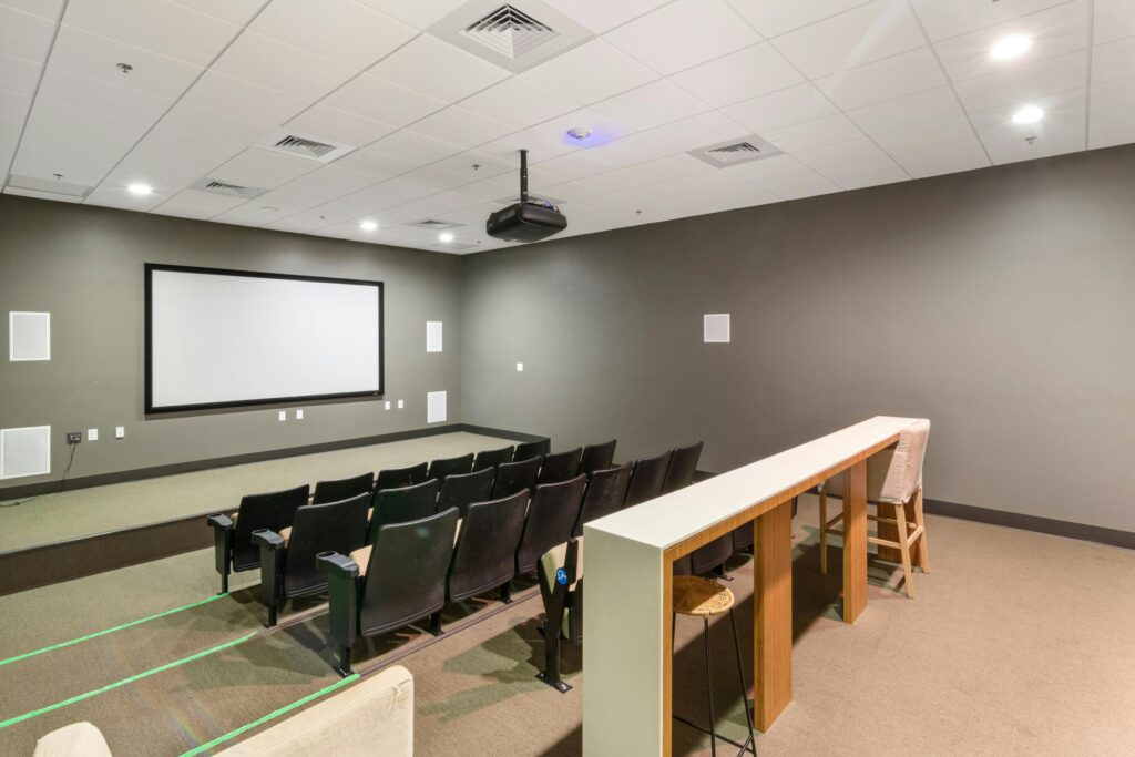 Spacious and modern empty cinema room with rows of comfortable chairs and a large screen.