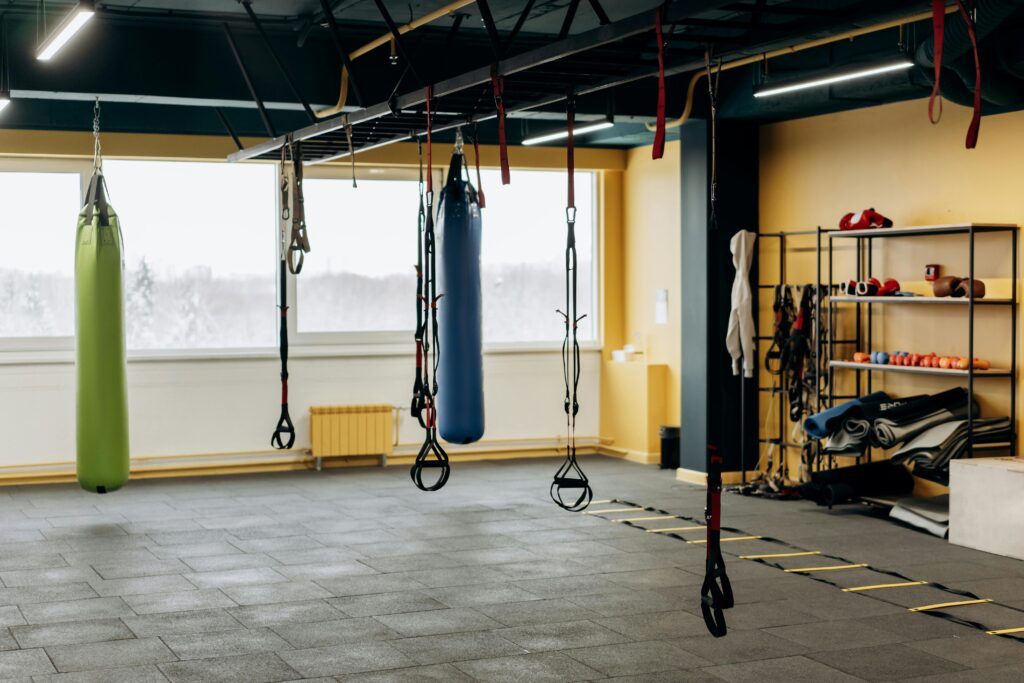 A modern gym with equipment, punching bags, and open space for workouts.